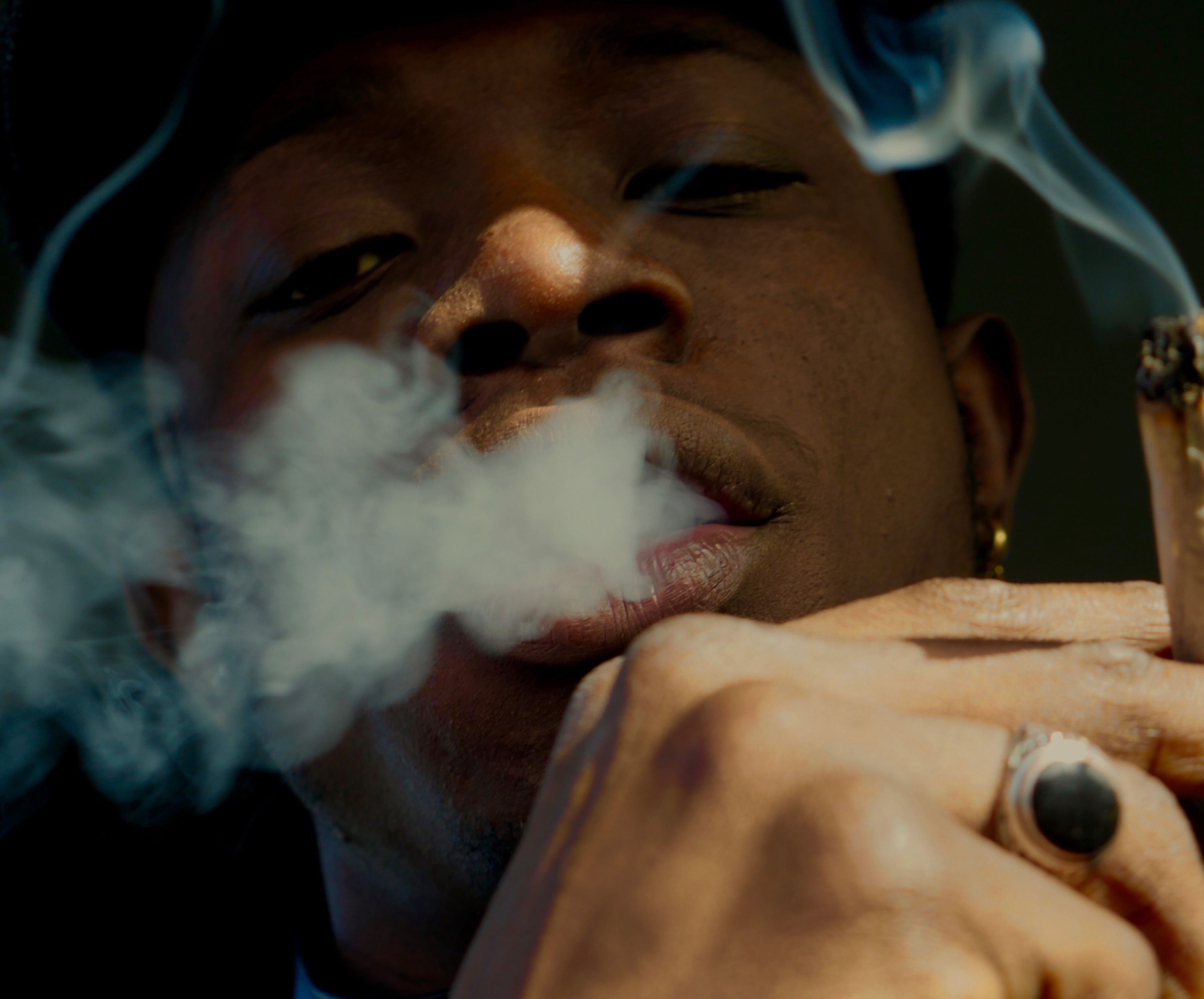 Close-up portrait of a person exhaling smoke.