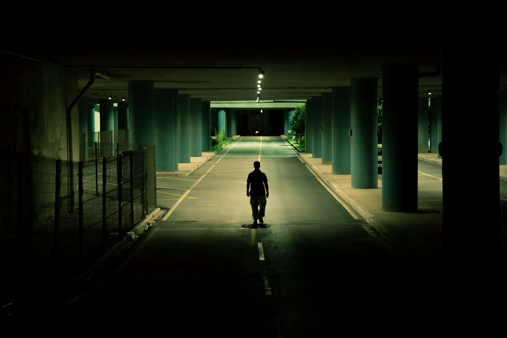 A solitary figure walking through a dimly lit underpass.